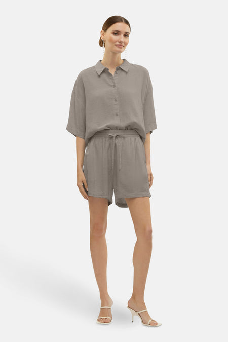 Short beige de VERO MODA, porté avec une chemise assortie et des sandales à talons.