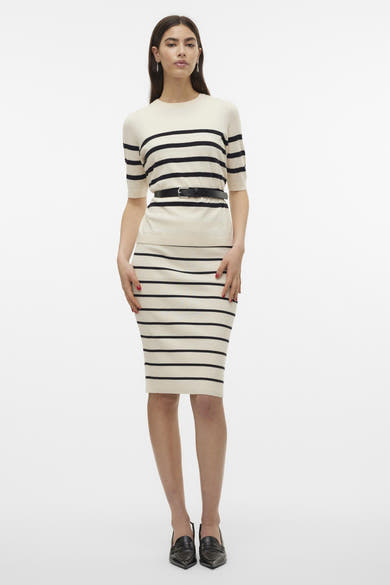 Pull écru de VERO MODA® à rayures noires horizontales, porté avec une jupe crayon assortie et des mocassins noirs pointus.