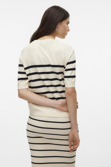 Pull col rond écru de VERO MODA® avec des rayures noires horizontales, porté avec une jupe assortie.