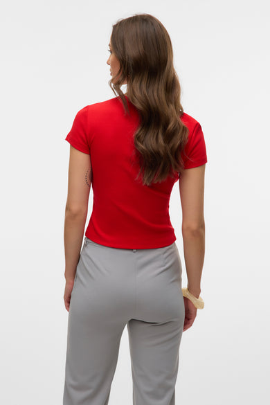 T-shirt rouge à manches courtes de VERO MODA, porté avec un pantalon gris et un bracelet beige, vue de dos.
