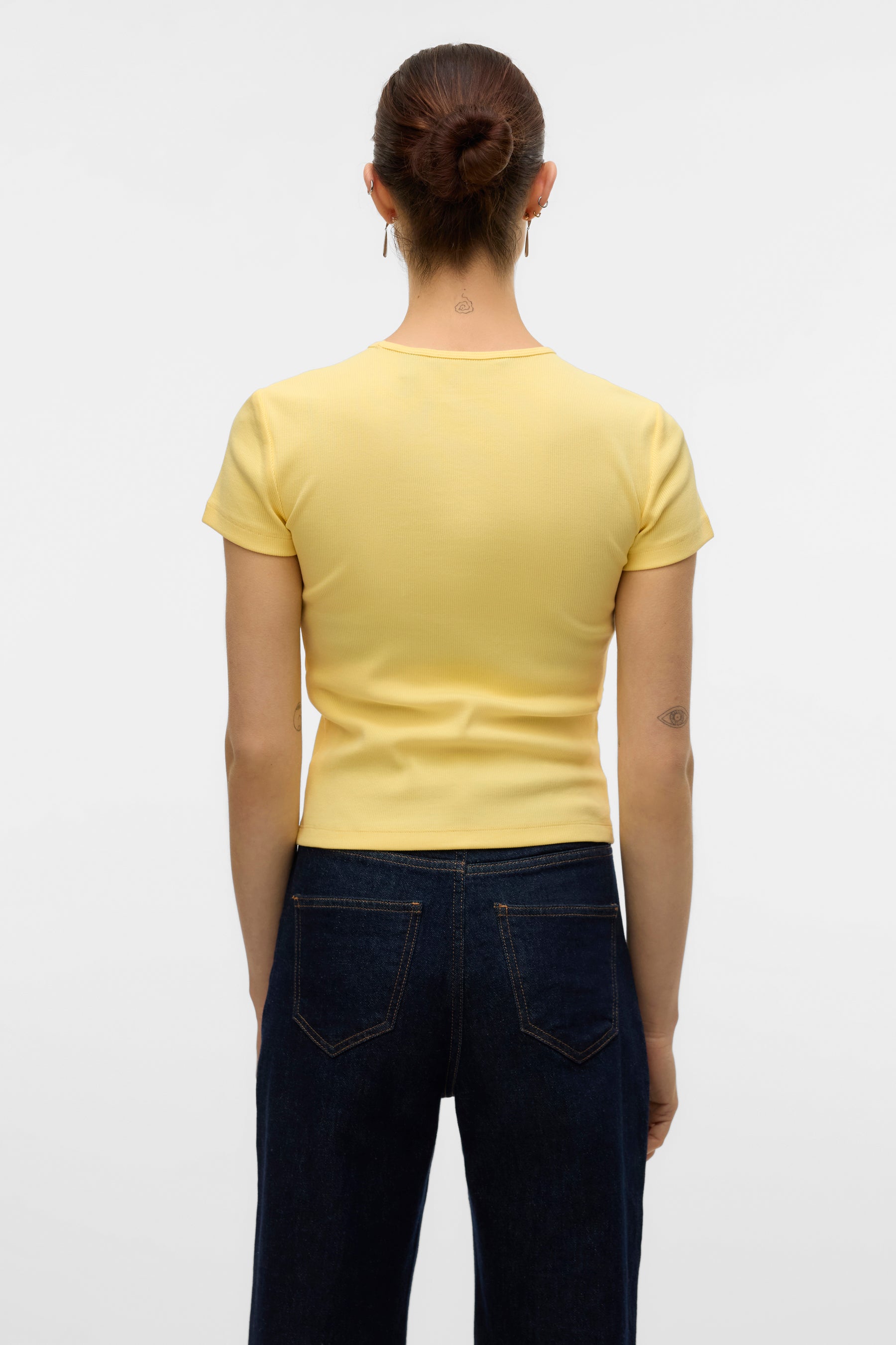 T-shirt jaune à manches courtes de Vero Moda, avec texture côtelée, porté avec un jean taille haute.