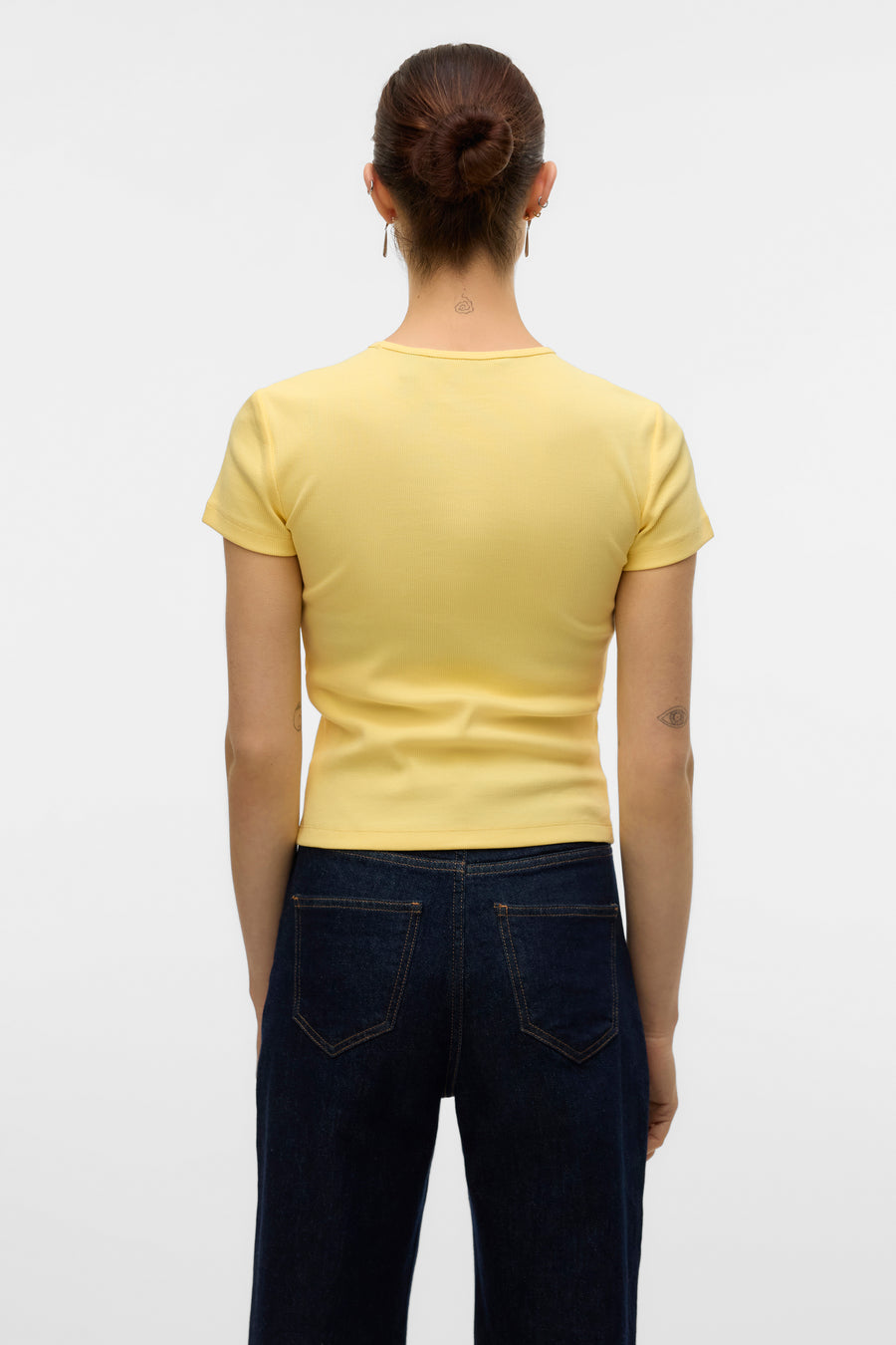 T-shirt jaune à manches courtes de Vero Moda, avec texture côtelée, porté avec un jean taille haute.
