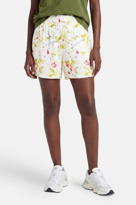 Short multicolore de VERO MODA à motif floral sur fond blanc, porté avec un t-shirt vert et des baskets.