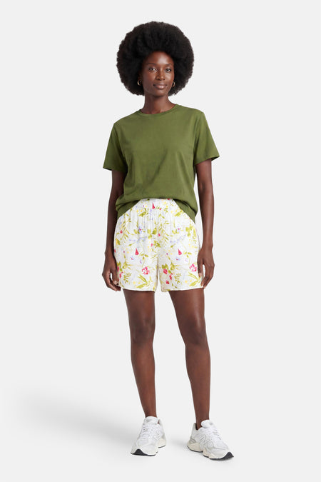 Short blanc à motif floral multicolore de VERO MODA, porté avec un t-shirt vert et des baskets blanches.