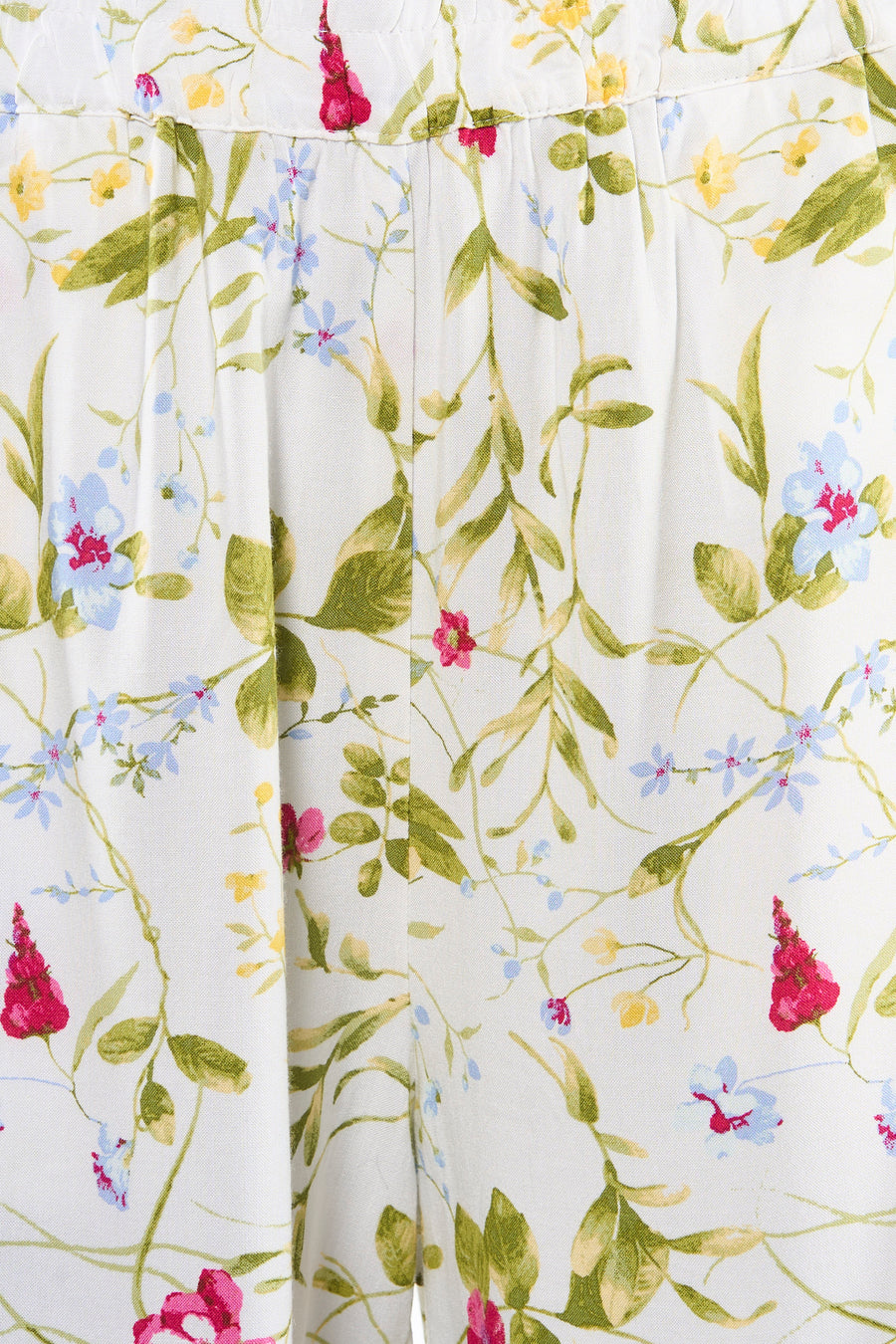 Short multicolore de VERO MODA avec motif floral sur fond blanc, des fleurs rouges, bleues et jaunes et des feuilles vertes, et des plis.