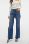 Jean large en denim bleu moyen de VERO MODA, porté avec un haut blanc à manches longues et des escarpins bleus.