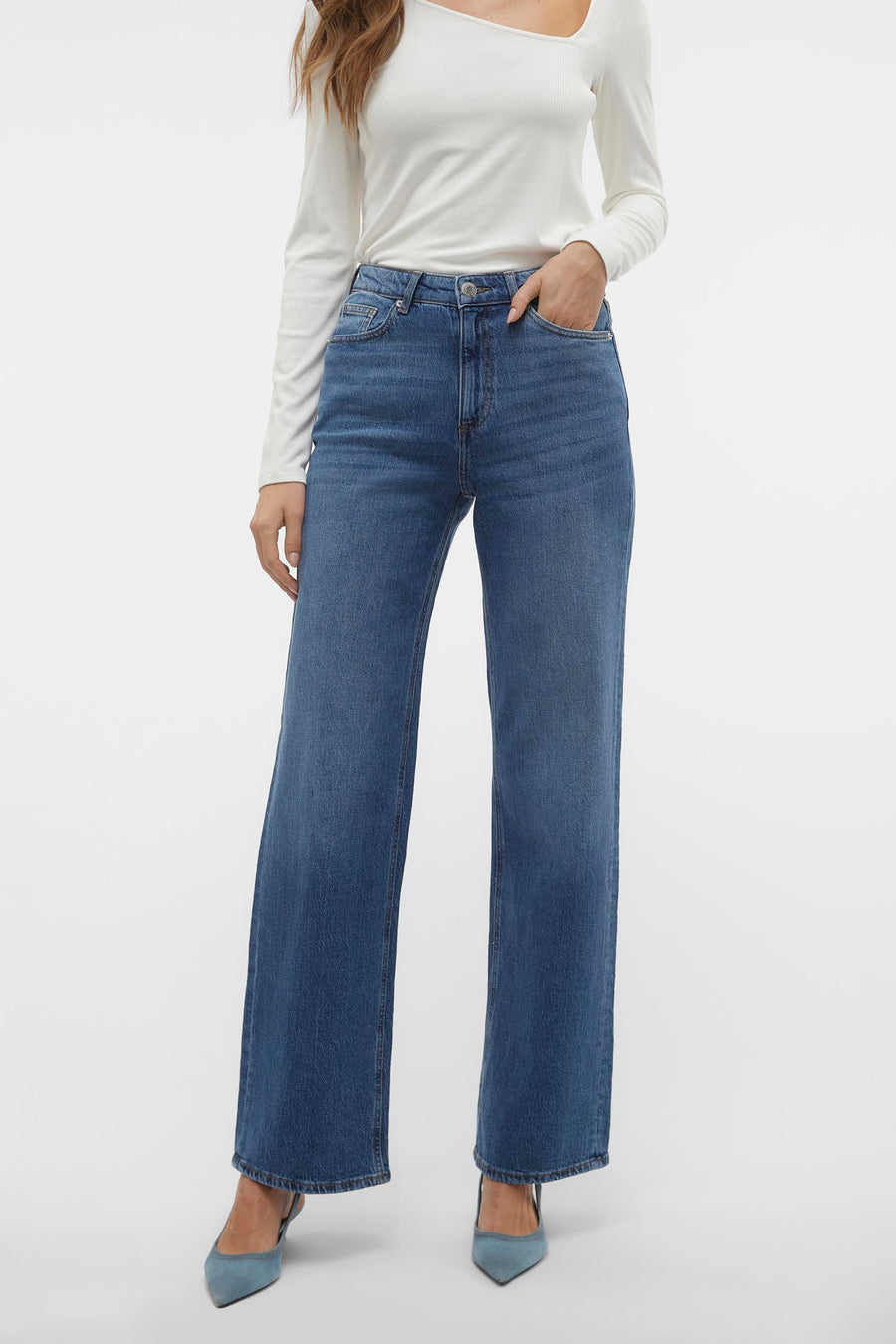 Jean large en denim bleu moyen de VERO MODA, porté avec un haut blanc à manches longues et des escarpins bleus.