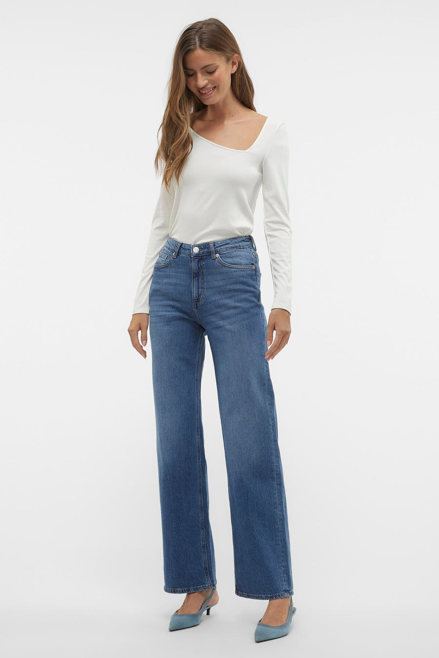 Jean large bleu moyen de VERO MODA, porté avec un haut blanc à col carré et des escarpins bleus.