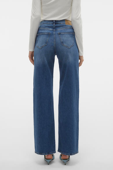 Jean large bleu moyen de VERO MODA, porté avec un haut blanc à manches longues et des talons aiguilles bleus.