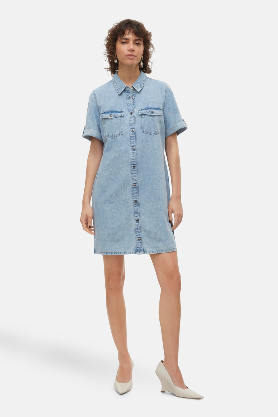 Robe en denim bleu clair de Vero Moda, boutonnée sur toute la longueur, portée avec des escarpins couleur crème.