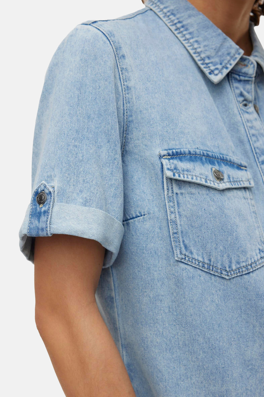 Robe en denim bleu clair de VERO MODA, avec poche de poitrine et manches courtes retroussées.