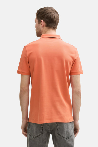 Oranje poloshirt met korte mouwen van Tom Tailor, van achteren gezien, gedragen met een grijze jeans.