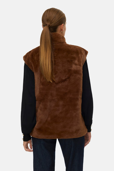 Veste sans manches marron imitation fourrure de VERO MODA, portée sur un pull noir et un jean bleu.