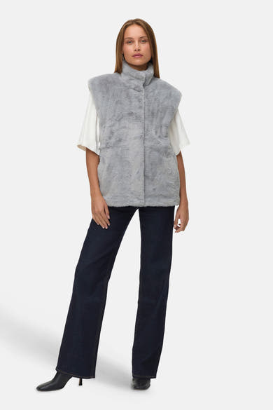 Veste sans manches grise en fausse fourrure par VERO MODA, portée sur un t-shirt blanc et un jean bleu foncé.