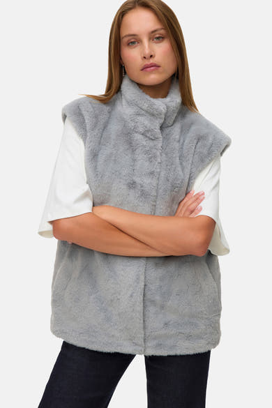 Veste sans manches grise en fausse fourrure de Vero Moda, portée avec un t-shirt blanc à manches courtes.