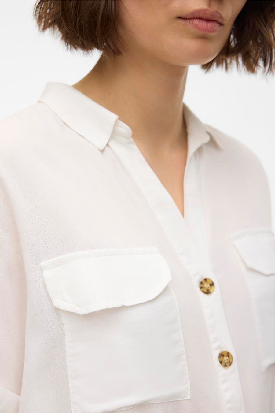 Chemisier blanc à manches courtes de VERO MODA® avec poches poitrine et boutons marron.
