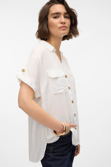 Chemisier blanc à manches courtes de VERO MODA, avec poches poitrine, boutons dorés et bracelet doré.
