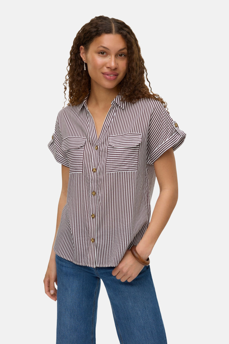 Chemisier à manches courtes multicolore de VERO MODA®, rayures verticales, poches poitrine, porté avec un jean et un bracelet.