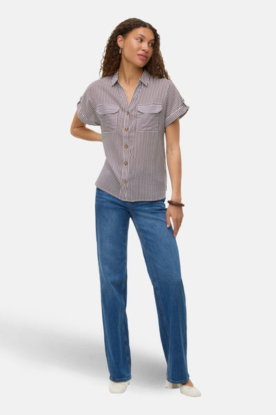 Chemisier à manches courtes multicolore de VERO MODA, rayures verticales, porté avec un jean bleu et des chaussures blanches.