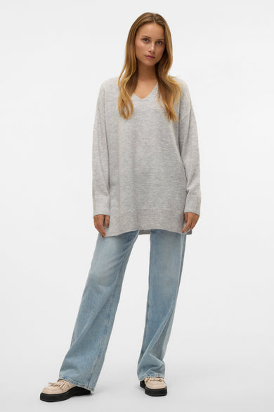 Pull à col en V gris de VERO MODA, porté avec un jean bleu large et des chaussures plateforme.