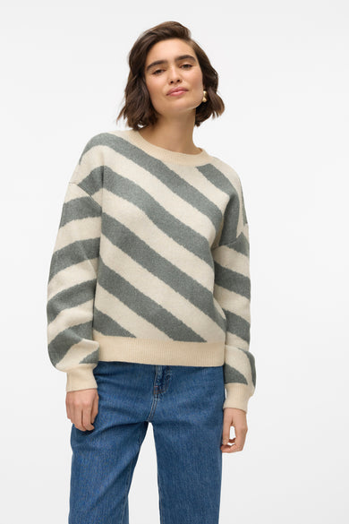 Pull à col rond beige de Vero Moda, à rayures grises en diagonale, porté avec un jean bleu.
