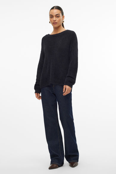 Pull noir à col rond de VERO MODA, porté avec un jean ample et des bottines en cuir.