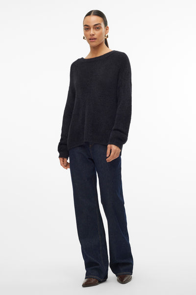 Pull noir à col rond de VERO MODA, porté avec un jean ample et des bottines en cuir.