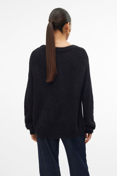 Zwarte rondehals trui van VERO MODA, gedragen met een high-waisted jeans, en paardenstaart kapsel.