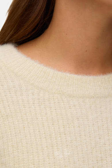 Crèmekleurige trui met ronde hals van VERO MODA, met gebreide textuurdetails, met gedeeltelijk zichtbare bruine nek en haar.