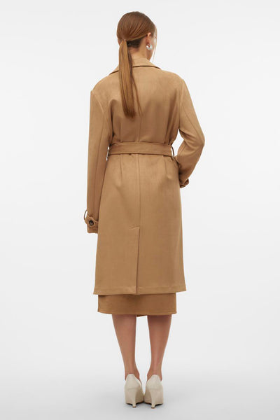 Veste longue marron de VERO MODA avec une ceinture, portée avec une jupe et des talons couleur crème.