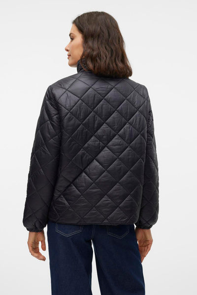 Veste courte noire de VERO MODA, matelassée avec motif losanges, portée avec un jean bleu foncé.