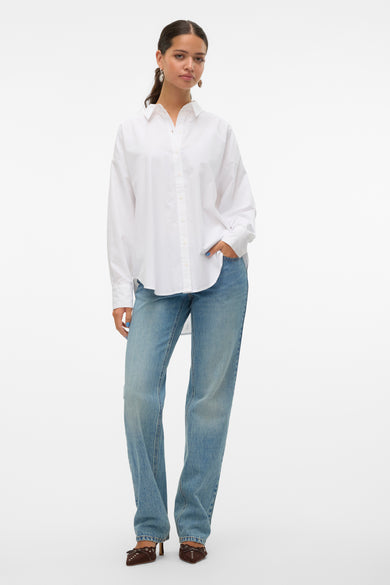 Chemise à manches longues blanche de VERO MODA, portée avec un jean bleu et des chaussures marron à talons.
