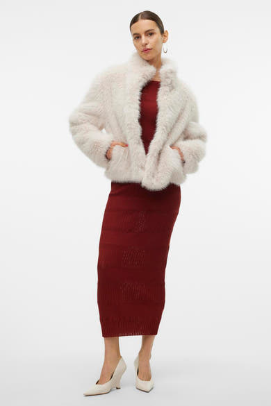 Veste courte écru de Vero Moda, portée sur une robe moulante bordeaux, avec des escarpins ivoire.