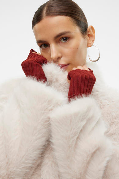 Ecru korte jas van VERO MODA, van zachte imitatiebont, gedragen met bordeauxrode wanten en oorringen.