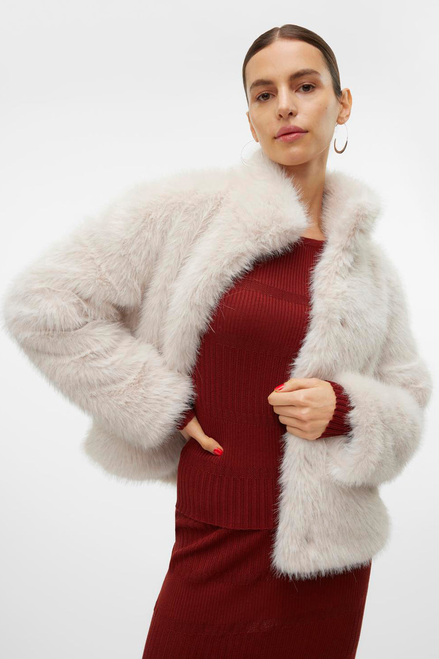 Ecru korte jas van VERO MODA, van pluizige imitatiebont, gedragen met een rode geribbelde set.