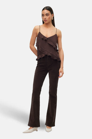 Pantalon évasé marron en velours côtelé de Vero Moda, porté avec un haut à fines bretelles et des escarpins ivoire.
