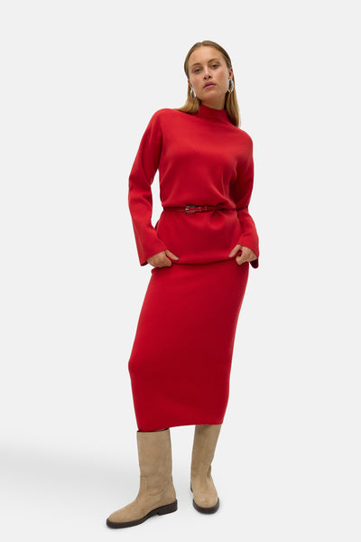 Midi-rok in rood van VERO MODA, gedragen met een bijpassende trui, dunne riem en beige suède laarzen.