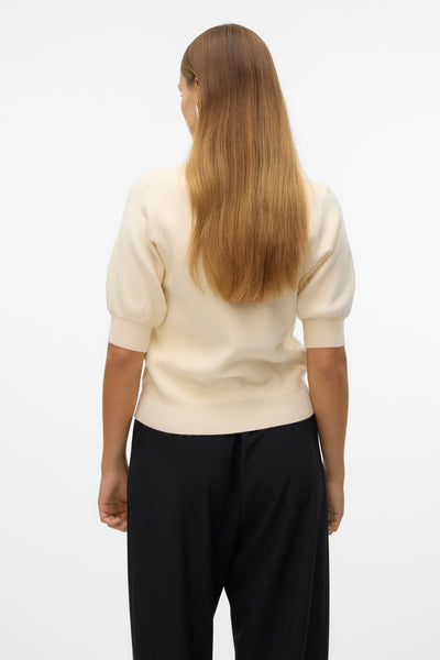 Ecru V-hals trui van VERO MODA, gedragen met een wijde zwarte broek, achtergezicht.