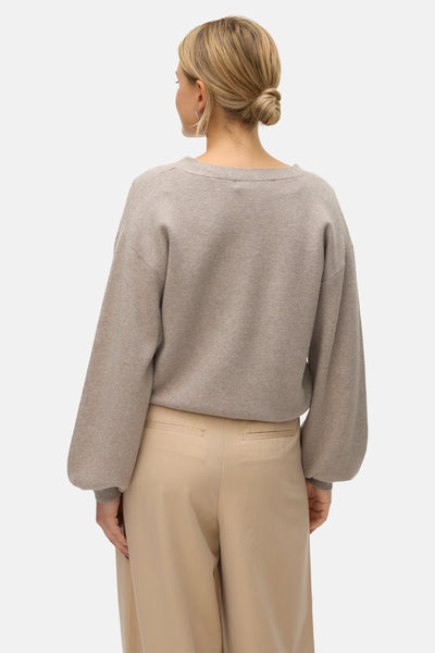 Cardigan beige de Vero Moda, manches longues bouffantes, porté avec un pantalon beige, vue arrière.
