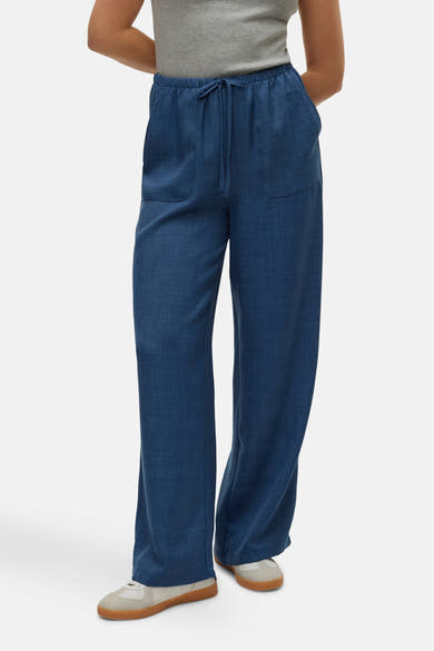 Pantalon coloré bleu par VERO MODA, avec une taille élastiquée à cordon, porté avec un haut gris et des baskets.