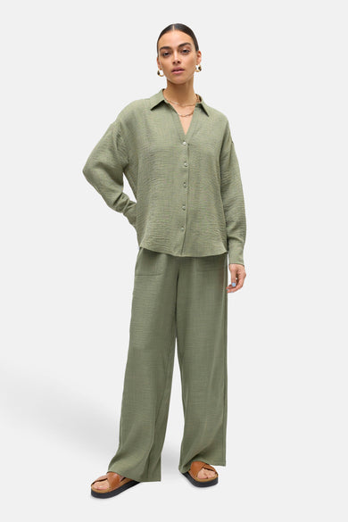 Pantalon vert texturé de VERO MODA, coupe ample avec poches et porté avec des sandales marron.
