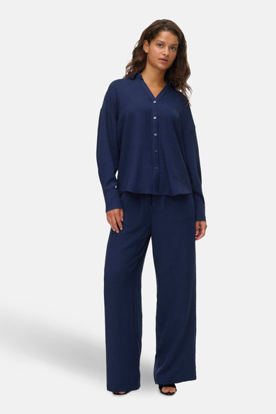 Pantalon coloré bleu de VERO MODA, ample et à texture gaufrée, porté avec une chemise assortie.
