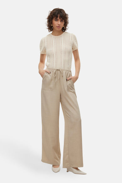 Pantalon beige de VERO MODA, à jambes larges, avec poches et cordon de serrage à la taille, porté avec un haut tricoté écru.

