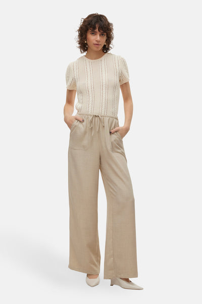 Pantalon beige de VERO MODA, à jambes larges, avec poches et cordon de serrage à la taille, porté avec un haut tricoté écru.
