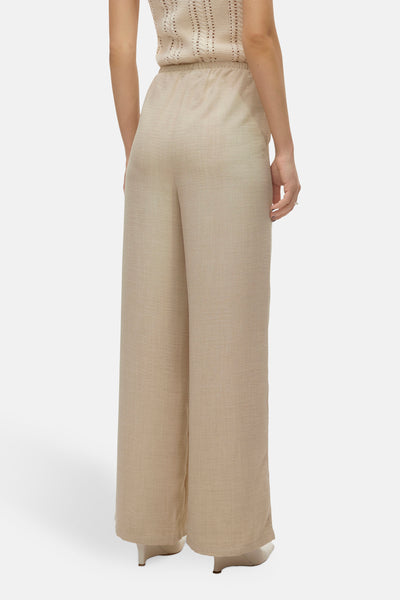 Pantalon coloré beige de VERO MODA, coupe ample et taille élastique, porté avec un haut assorti.
