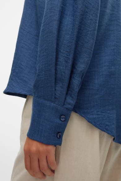 Chemise bleu à manches longues de VERO MODA, avec fermeture boutonnée au poignet et un tissu texturé.
