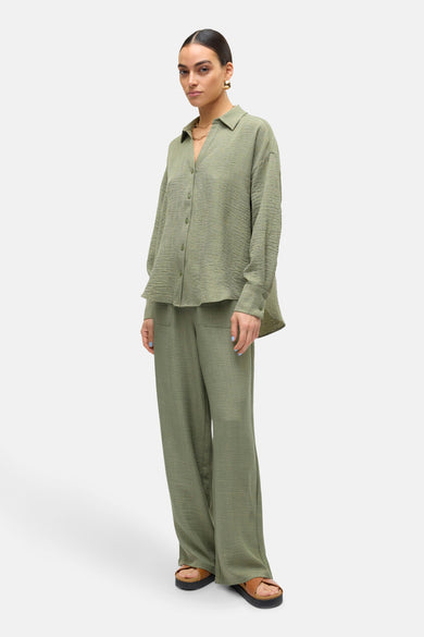 Chemisier à manches longues vert de VERO MODA, avec une texture froissée et un pantalon assorti.