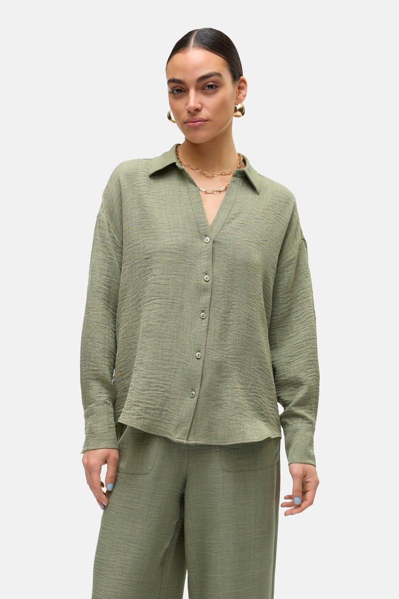 Chemisier à manches longues vert de VERO MODA, texturé avec chaîne dorée et boucles d'oreilles.