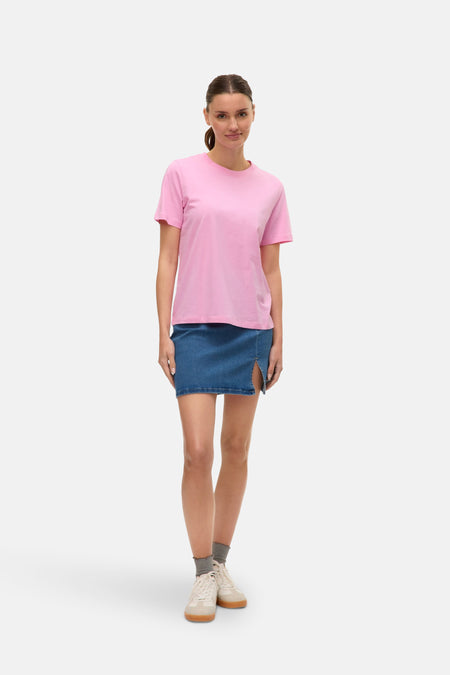 Roze T-shirt met korte mouwen van VERO MODA, gedragen met een korte spijkerrok en sneakers.