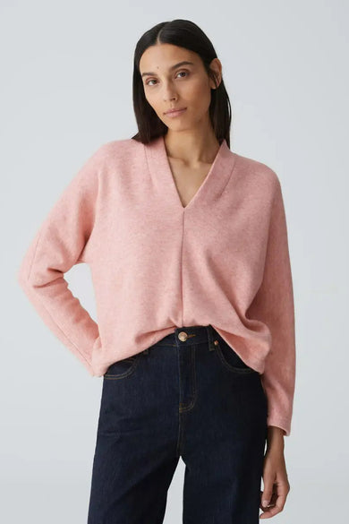 Oranje pull van OPUS, met V-hals, gedragen met een donkere jeans en een gouden knoop.